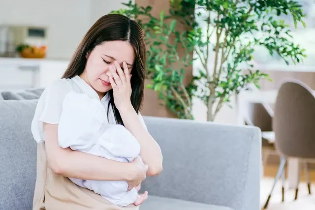 赤ちゃんを抱いて疲れた様子の女性